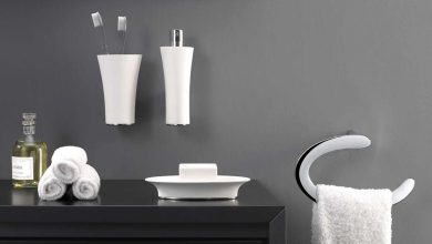 A bathroom with a sleek black counter with smart & stylish accessories on it and neatly folded white towels