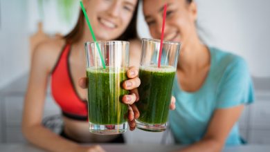 Two women showcasing green vegan drinks in glasses.